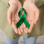 Woman holding a green ribbon signifying Traumatic Brain Injury Awareness