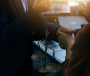 Client shaking hands with a lawyer at a desk, with justice scales in the foreground—symbolizing trust, legal support, and the commitment of no cost–injury lawyers to fight for clients without upfront fees.