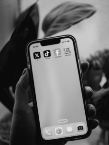 Phone in hand showing social media, and social media use can impact your case.