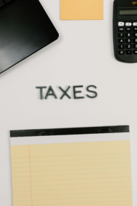 Notepad and calculator on desk with 'Taxes' spelled out — representing personal injury settlement taxes.