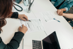 A legal professional reviews paperwork with a couple during a consultation, highlighting the support clients need when facing legal challenges.