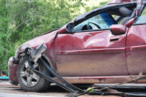 Wrecked red car with shattered windows after a crash, highlighting the impact of dangerous intersections in Jefferson County.