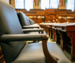 Empty courtroom chairs and microphones before a legal conference, reflecting the leadership and professionalism of an experienced personal injury attorney.