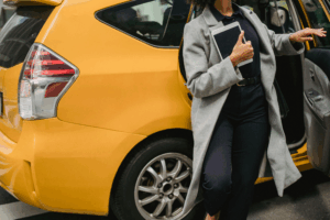 Woman stepping out of a yellow rideshare car, representing the rideshare passenger accident experience and the importance of safety awareness.