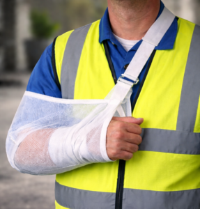 Construction worker with arm in sling after workplace injury related to workers' compensation covered injuries